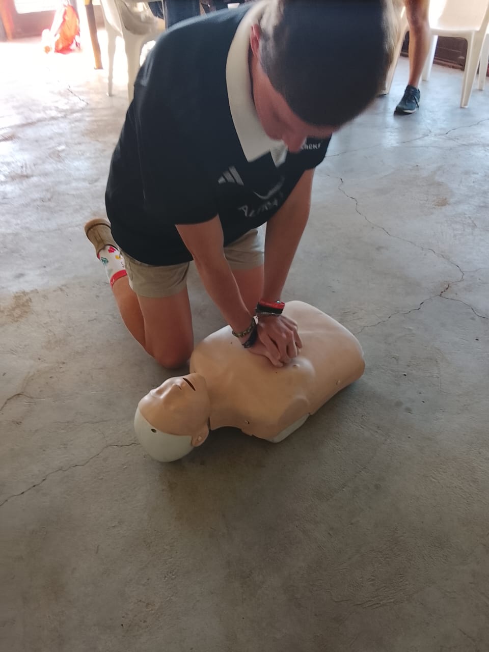 Student performing chest compressions on a CPR mannequin during hands-on first aid training